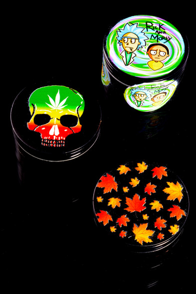 Assorted black 2.25-inch 4-piece aluminum grinders with colorful decals on black backdrop; wholesale head-shop selection photo.