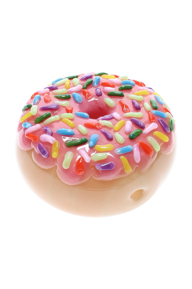 Pink-frosted donut glass pipe with raised rainbow sprinkles; 2.5" borosilicate novelty for wholesale head-shop buyers, angled studio cutout showing bowl rim.
