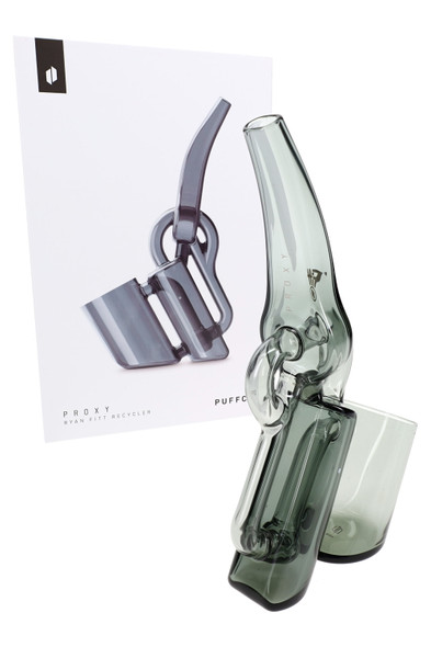 Recycler glass posed beside Puffco retail box, three-quarter angle; shelf-ready packaging emphasized for B2B resale.