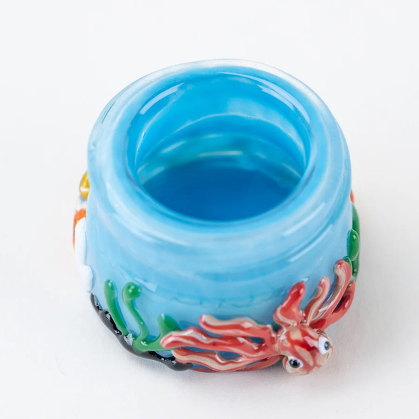 Head-shop supplies blue glass terp jar top view showing octopus and seaweed lampwork around rim.