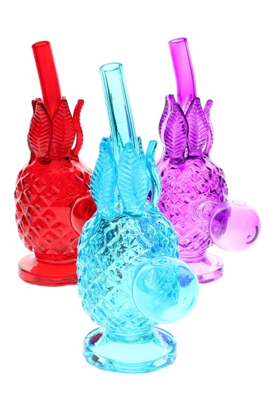 Three 5.5" colored glass pineapple oil burner rigs—red, aqua, purple—on white; wholesale head-shop display, angled view with textured leaves and sturdy base.