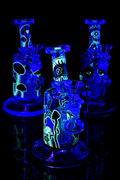 Trio of 6.5" mushroom water pipes glowing under blacklight; tree perc visible, assorted designs; promotional angle for head-shop displays.