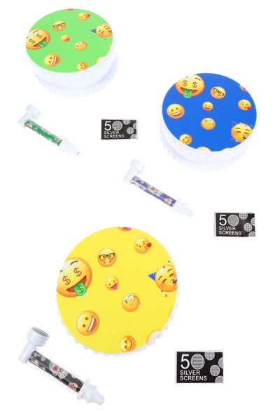 Bright emoji-lid 4" plastic grinders with matching metal pipes and 50-pack screens, assorted colors, retail smoke-shop gift set flat lay.