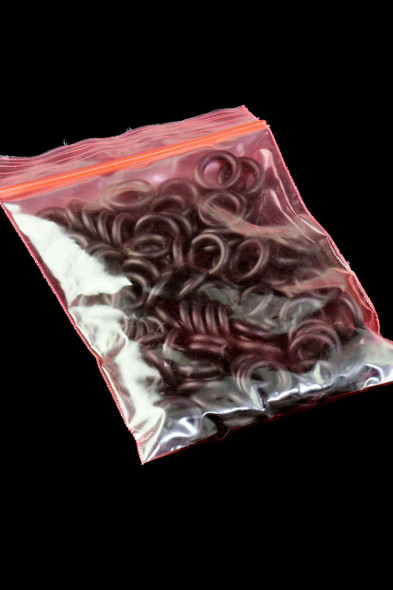 Pink-zip poly bag filled with black 9 mm O-rings; head-shop supplies pack, high-contrast studio shot on black background.