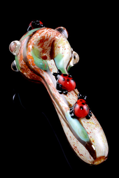 4.5" glass spoon with three red ladybugs, speckled tan bowl and green swirls, angled on black—wholesale head-shop pipe with clear grip marbles.