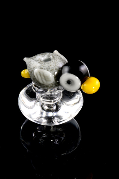 Closeup of penguin carb cap with clear base, gray and black body and yellow beak; accessory shown at angle for wholesale catalog.