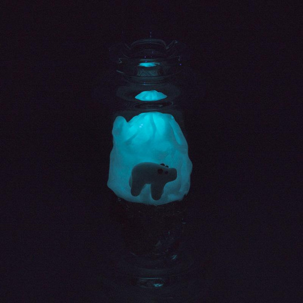 Dark room shot showing bright blue glow-in-the-dark iceberg inside the glass; UV reactive feature for retail smoke gear.