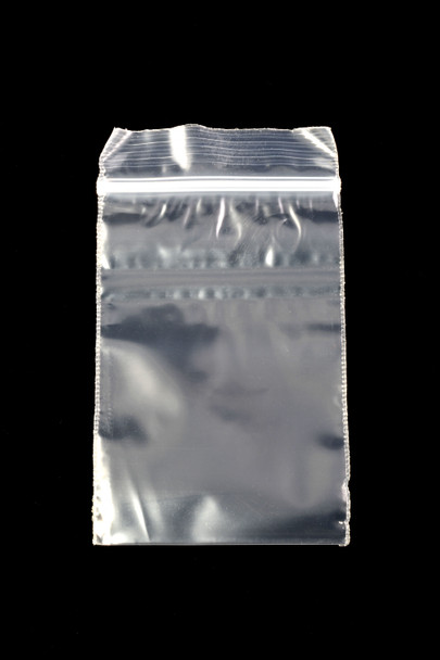 Wholesale 2 × 3 inch clear apple-print zip-top baggie, red apple icon centered, empty pouch on black background, overhead studio view