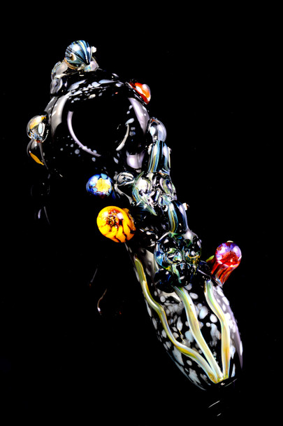 Dark ocean-theme glass spoon for head-shop buyers, 4.5" US-made with raised sea-life accents and reef marbles, dramatic angled top view on black.