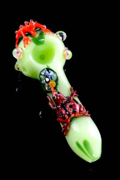 Light-green 4.5" glass spoon for head-shop buyers with red and brown frogs, lily-pad marble accents, top-down bowl view on glossy black background.
