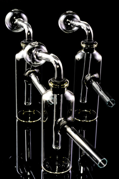 Three 4" clear glass bottle oil burner bubbler rigs on black, globe heads with grommet seals; US-made piece for smoke-shop wholesale buyers.