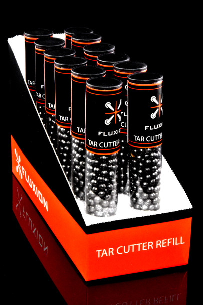 Bulk wholesale display of 12 Flux tar cutter refill tubes in angled orange counter box on black background