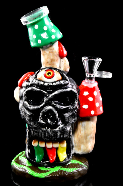 Front 8.5" GoG skull water pipe with rasta teeth, honeycomb perc, red/green mushroom accents; retail smoke gear on black background.