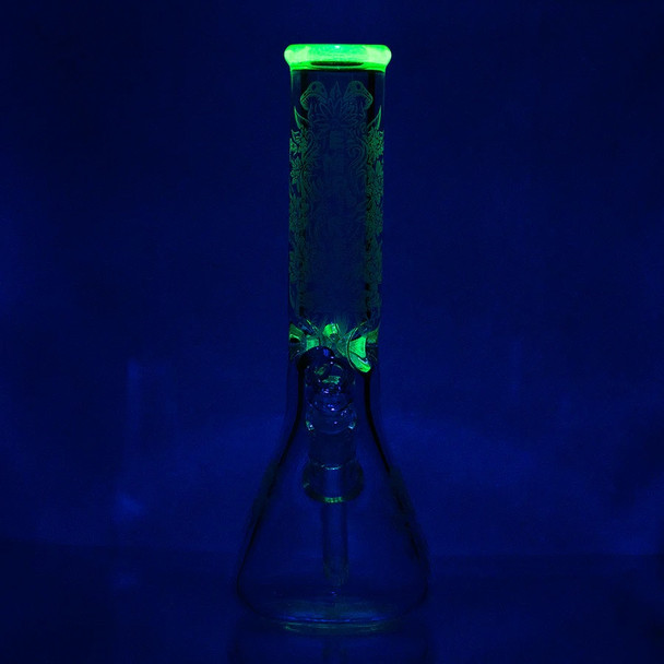 UV-reactive beaker rim glowing green under blacklight; sandblasted floral artwork visible for B2B product listing.