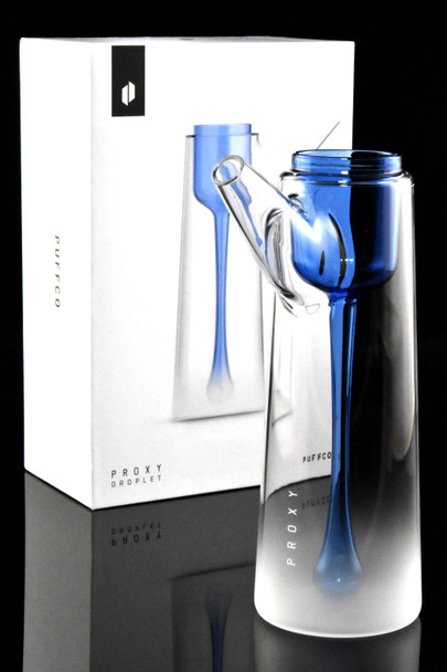 Puffco Proxy Droplet posed before branded retail box, reflective studio angle; gradient-frosted glass water attachment for wholesale accessory buyers.