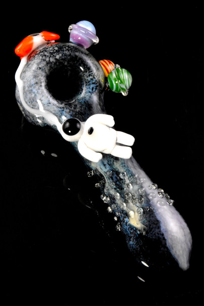 Overhead three-quarter view on black of galactic spoon with planets and rocket; textured bubble trail along handle for wholesale product pages.