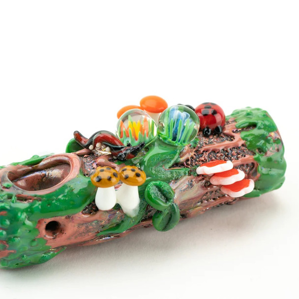 Rear angle highlighting carb placement and wood-grain texture on mossy log pipe; compact 4" hand pipe for wholesale listings.