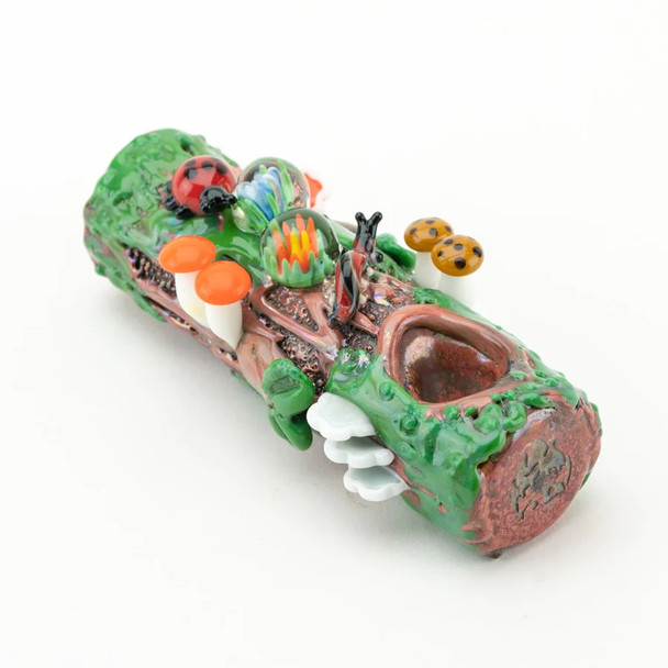 Side profile of mossy log dry pipe showing bark grooves and bowl opening; artisan borosilicate for retail smoke gear catalogs, clean white cutout.