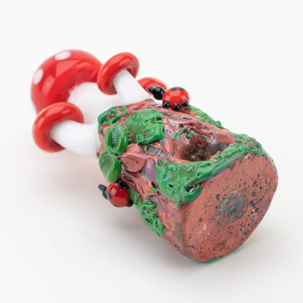Rear view of toadstool pipe highlighting textured base, vines, and ladybug details; B2B showcase glass, close studio angle.