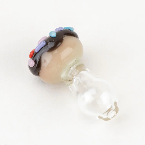 Angled white-background view of donut Peak Pro glass ball cap; tan pastry body, black frosting, red/purple/blue sprinkles for smoke-shop retail. Angled white-background view of donut Peak Pro glass ball cap; tan pastry body, black frosting, red/purple/blue sprinkles for smoke-shop retail.