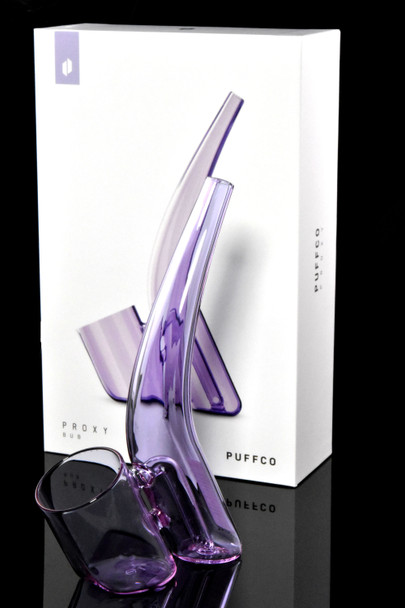 Bloom Proxy Bub posed beside white Puffco box on reflective black; lavender attachment and retail packaging emphasized for B2B buyers.