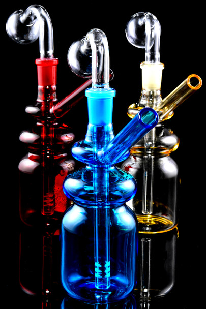 5.5" glass-on-glass bottle oil burner rigs in blue, red, and amber with clear domes on glossy black—wholesale head-shop trio, front angle.
