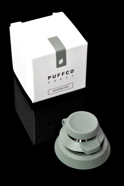 Flourish green Proxy Joystick Cap beside white Puffco retail box on black; shelf-ready packaging emphasized for wholesale buyers.