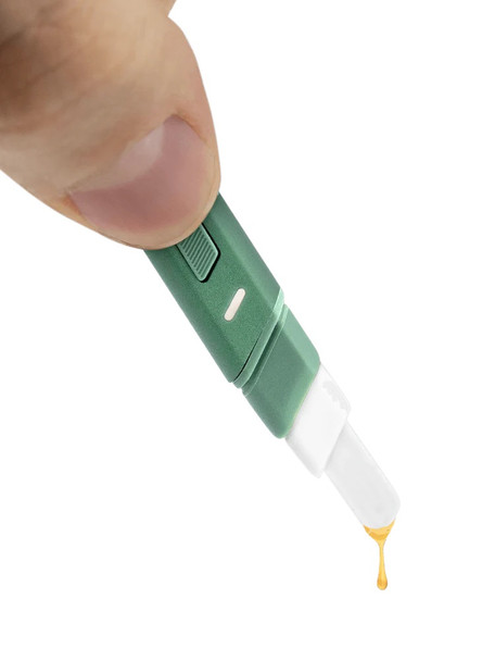 Macro of Flourish green Hot Knife dispensing a golden drop from heated ceramic tip; clean demo image for wholesale concentrate accessory pages.