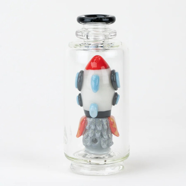 Glow-in-the-dark rocket ship Peak attachment inside clear glass, dark studio side angle; 4.5" worked piece for wholesale head-shop buyers.