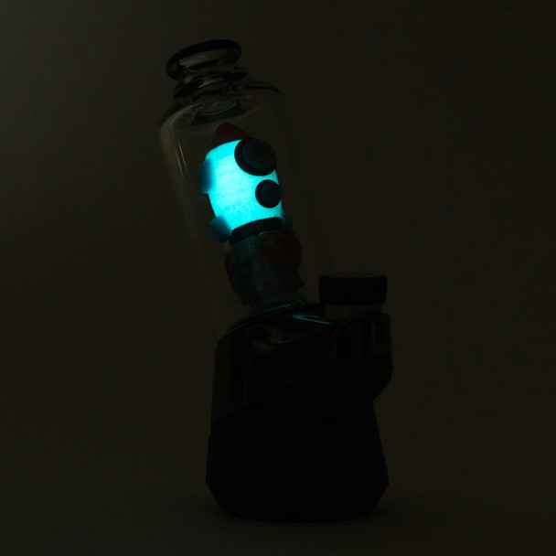 UV-lit side profile on Peak base highlighting turquoise glow and exhaust detail; glass attachment photographed for wholesale catalog.