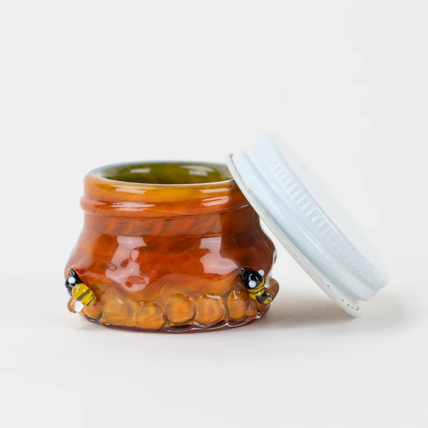 Amber honeycomb glass terp jar with lid ajar, tiny lamp-worked bees on rim—1.5" US-made storage, head-shop wholesale accessory, side angle.