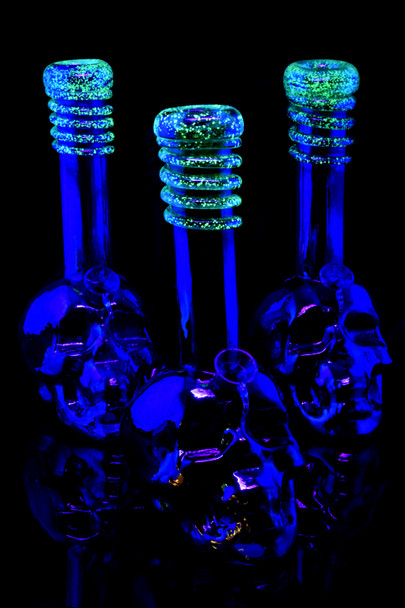 Wholesale 10.5-inch metallic skull soft glass water pipes with glow-dark swirl necks, trio black-light front view.