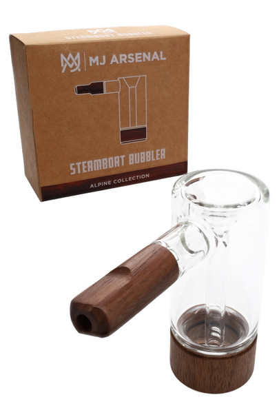 MJ Arsenal Steamboat Bubbler beside Alpine Collection retail box, clear glass with dark walnut accents; compact wholesale water pipe shown side angle. MJ Arsenal Steamboat Bubbler beside Alpine Collection retail box, clear glass with dark walnut accents; compact wholesale water pipe shown side angle.