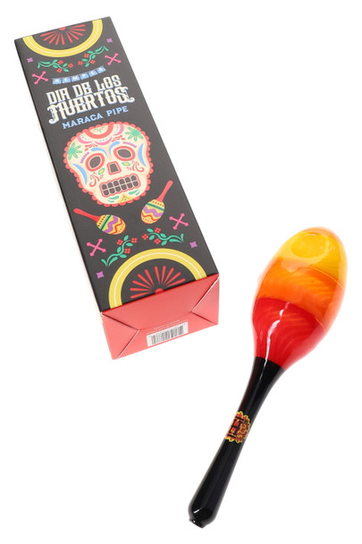 Hemper Dia De Los Muertos maraca hand pipe lying beside tall black sugar-skull retail box, styled product shot for smoke shop shelf displays.