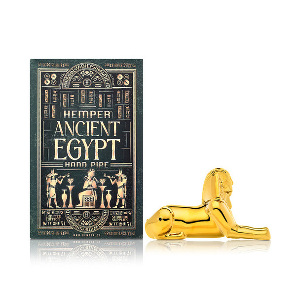 Side profile of 5" gold Hemper Ancient Egypt sphinx hand pipe beside ornate green gift box, ideal hero image for smoke shop online listings.