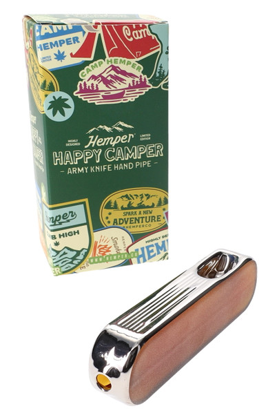 Hemper Happy Camper army knife hand pipe posed in front of green camp-themed retail box, showing shelf-ready packaging for head-shop displays.