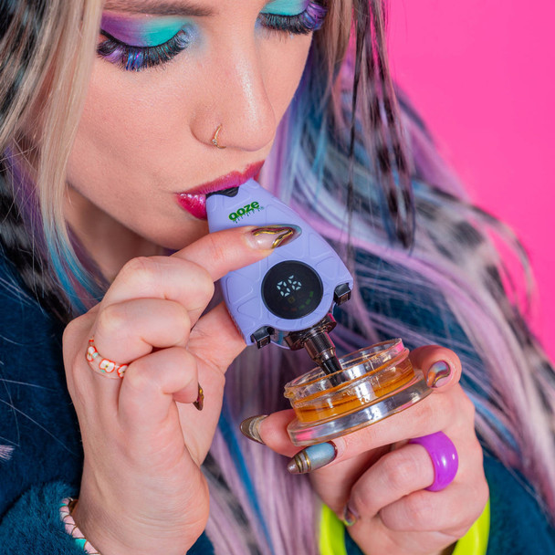 Lifestyle photo of Ooze Hover concentrate vaporizer in lavender finish being used with a concentrate jar, featuring a digital display screen