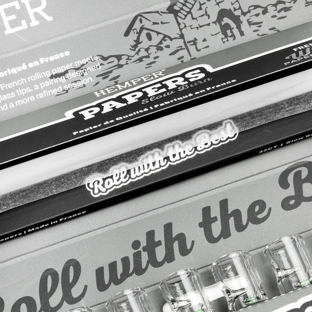 Close-up of open HEMPER combo pack showing rolling paper compartment and clear glass tips below