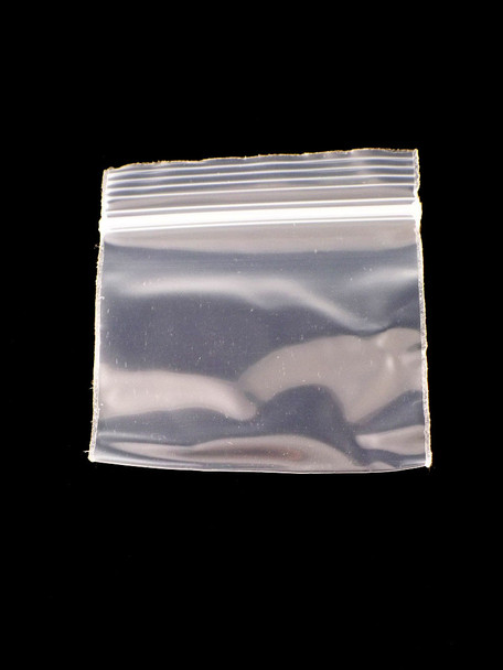 Wholesale 2-inch × 2-inch clear plastic mini zipper baggie, single pouch on black backdrop, showing sturdy resealable seal and square profile for retail buyers.
