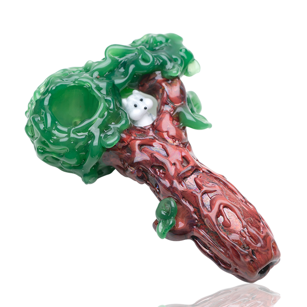 Tree-trunk spoon pipe with sculpted leaves and canopy, white squirrel peeking, studio cutout on white—retail smoke-shop art-glass piece.