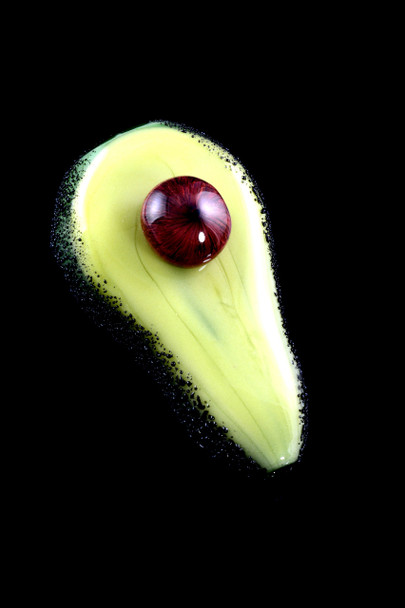 Overhead studio shot of 3" avocado-green glass dry pipe on black, with red-brown pit accent—head-shop wholesale listing angle showing glossy finish.