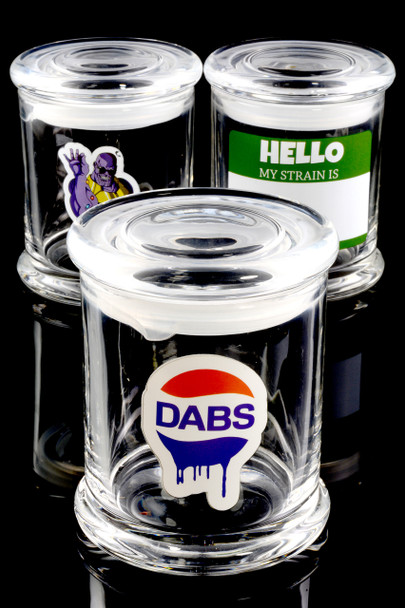 Wholesale 3.75-inch clear glass stash jars with mixed cartoon decals, black-background trio shot highlighting thick lid and deep storage capacity.