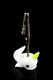 White glass narwhal with lime horn holding a metal alligator clip on braided stem, glossy black backdrop—wholesale roach clip accessory, case-ready.