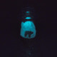 Dark room shot showing bright blue glow-in-the-dark iceberg inside the glass; UV reactive feature for retail smoke gear.