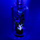 UV-lit close-up of ocean motif glowing bright blue and white; UV-reactive borosilicate highlight for wholesale catalog images.