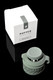 Flourish green Peak Pro Joystick Cap beside white Puffco retail box, reflective black background; silicone-steel build highlighted for wholesale accessory buyers.