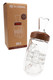 MJ Arsenal Halo Peak Top beside Alpine Collection retail box; clear glass body with walnut accent and handle, head-shop accessory shown angled. MJ Arsenal Halo Peak Top beside Alpine Collection retail box; clear glass body with walnut accent and handle, head-shop accessory shown angled.