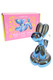 Blue Hemper Balloon Dog bong posed in front of pink gift box with balloon dog artwork, shelf-ready novelty water pipe display for head-shop inventory planners.