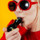 Person using Goody Glass Penguin hand pipe with black body and yellow beak against yellow backdrop