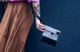 Person carrying a gray and black GRAV smell-proof pouch by the wrist strap to demonstrate compact portable design